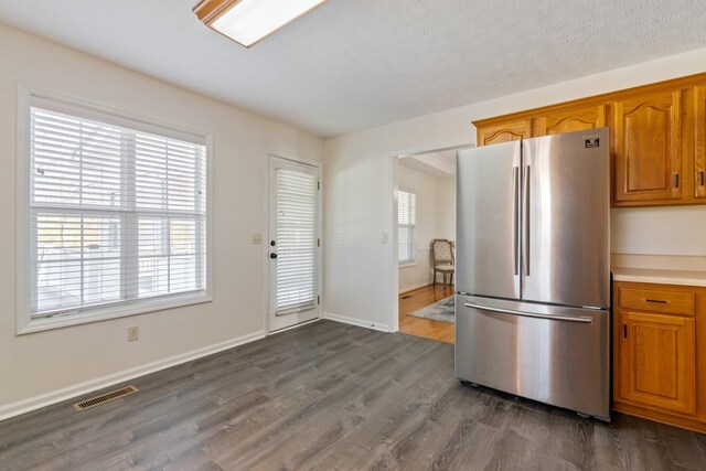 kitchen featuring stainless steel refrigerator, dark hardwood / wood-style flooring, and a textured ceiling