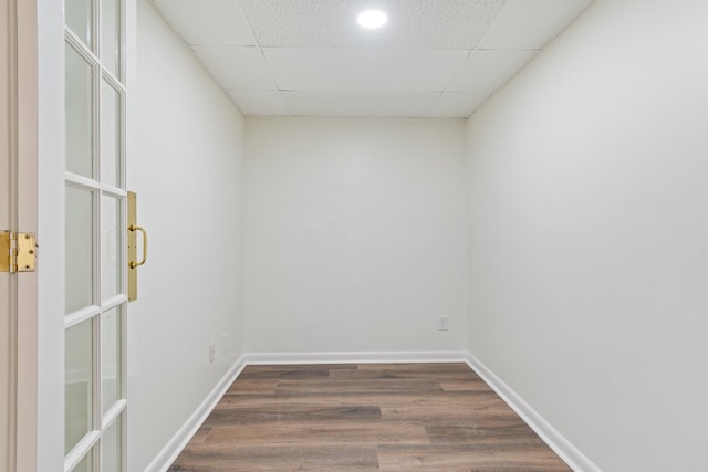 empty room with a drop ceiling and dark wood-type flooring