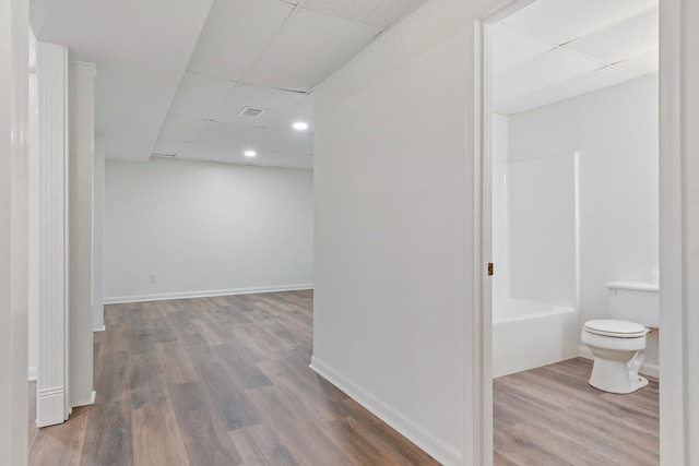 hall featuring hardwood / wood-style floors and a drop ceiling