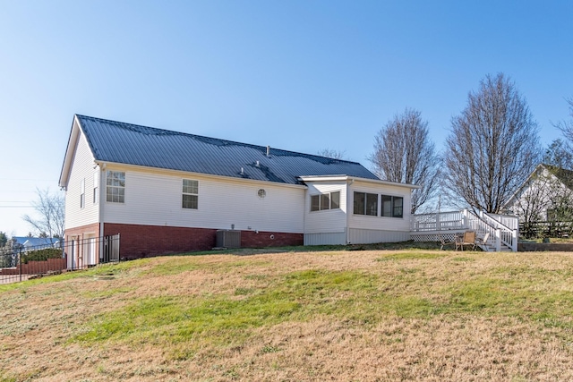 rear view of property featuring a yard, a deck, and central air condition unit