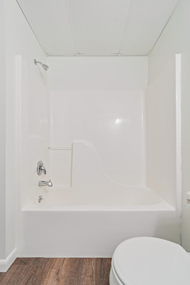 bathroom with toilet, washtub / shower combination, and hardwood / wood-style flooring