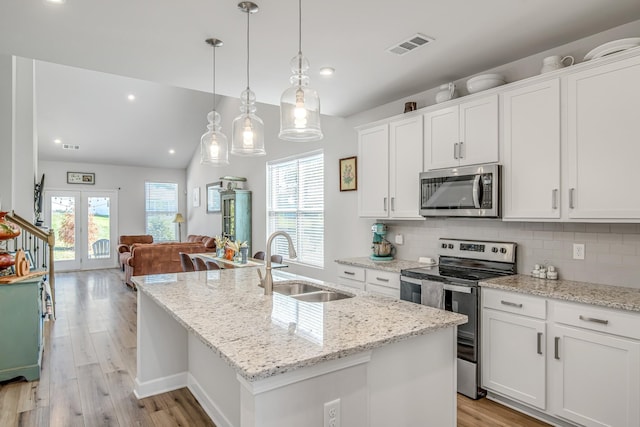 kitchen featuring appliances with stainless steel finishes, sink, a center island with sink, white cabinets, and hanging light fixtures