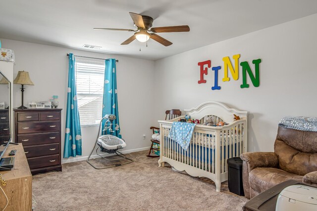 bedroom with ceiling fan, light colored carpet, and a crib