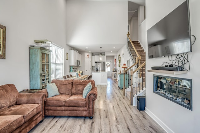 living room with a towering ceiling and light hardwood / wood-style floors