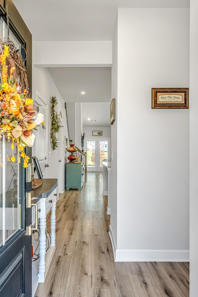 corridor with french doors and light hardwood / wood-style flooring