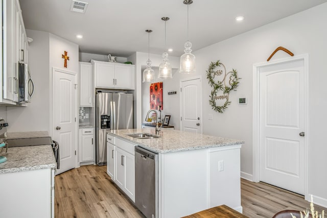 kitchen featuring appliances with stainless steel finishes, sink, a center island with sink, decorative light fixtures, and white cabinets