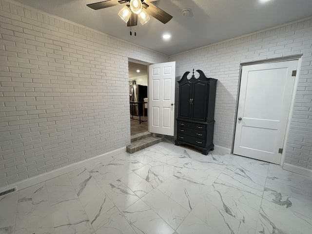 unfurnished bedroom with ceiling fan, crown molding, and brick wall