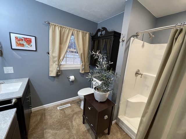 bathroom with a textured ceiling, vanity, toilet, and curtained shower