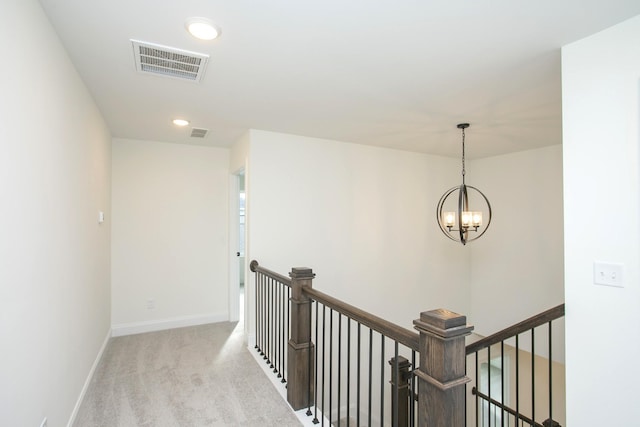 hall with light colored carpet and a chandelier