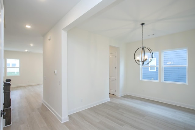 spare room featuring light hardwood / wood-style flooring and a chandelier