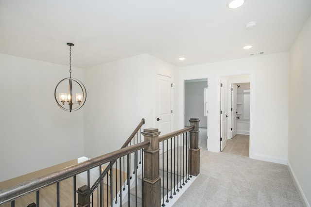 hall featuring light carpet and a chandelier