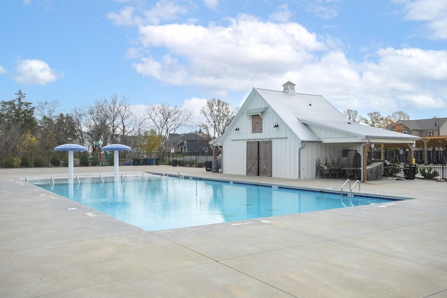 view of pool featuring an outbuilding, pool water feature, and a patio