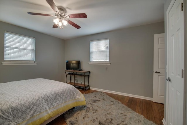 bedroom featuring ceiling fan, dark wood-type flooring, and multiple windows