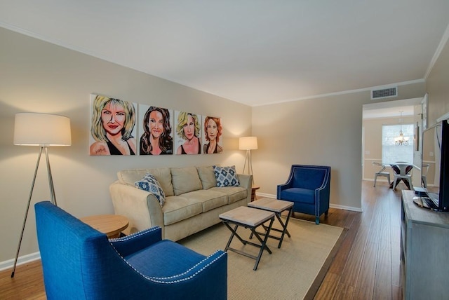 living room featuring hardwood / wood-style flooring, crown molding, and a chandelier