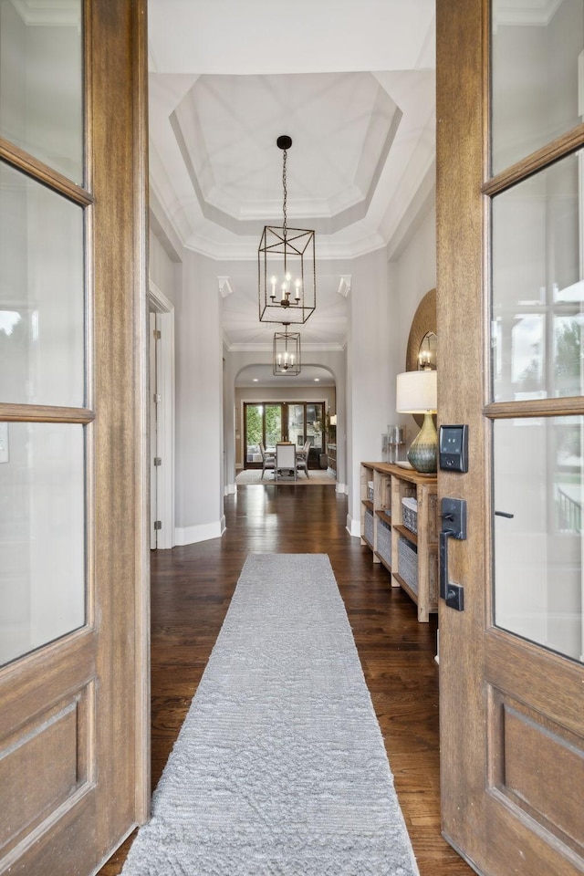 entrance foyer featuring a tray ceiling, dark hardwood / wood-style flooring, a chandelier, and ornamental molding