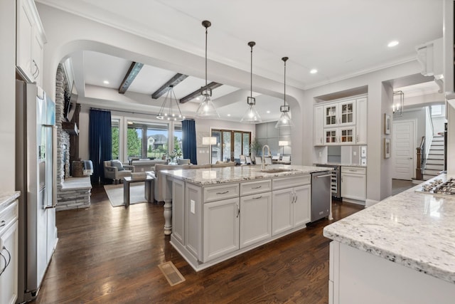 kitchen with white cabinetry, a kitchen island with sink, and hanging light fixtures