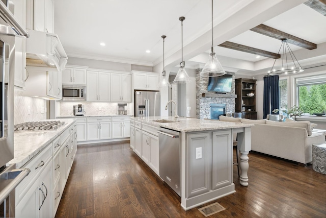 kitchen featuring a center island with sink, white cabinets, sink, decorative light fixtures, and stainless steel appliances