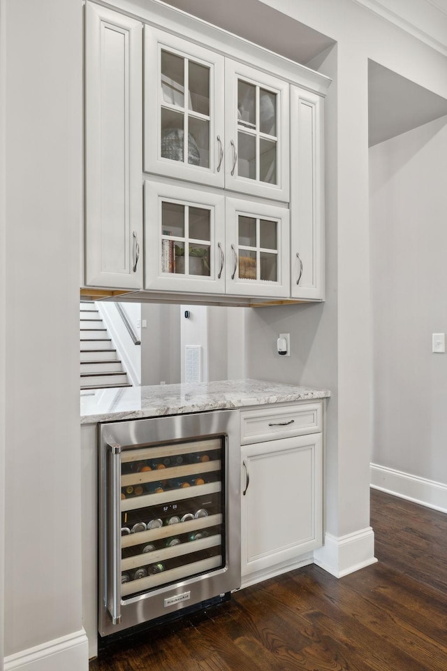 bar featuring white cabinets, dark hardwood / wood-style floors, light stone countertops, and beverage cooler