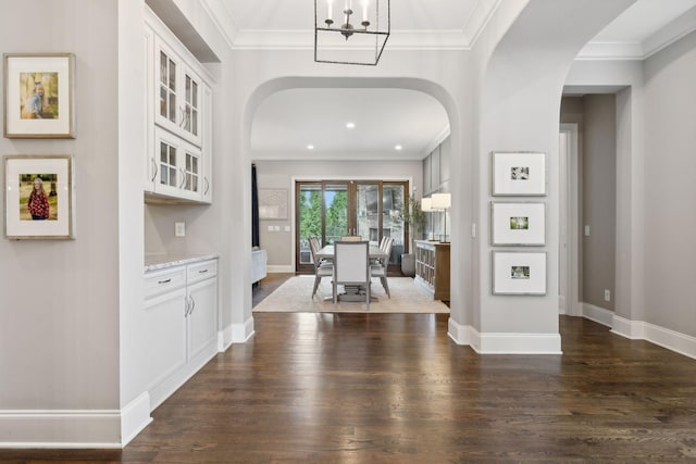 foyer entrance featuring dark hardwood / wood-style flooring, a chandelier, and ornamental molding