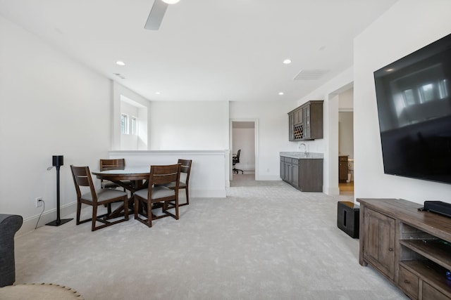 dining space with light colored carpet, ceiling fan, and sink