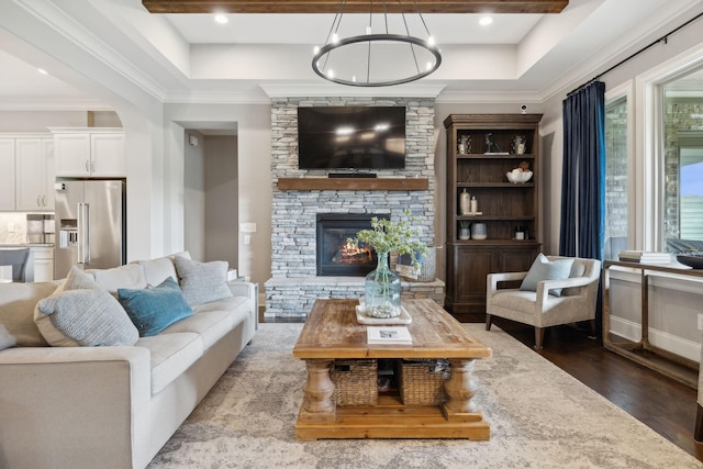 living room featuring a chandelier, hardwood / wood-style flooring, and a stone fireplace