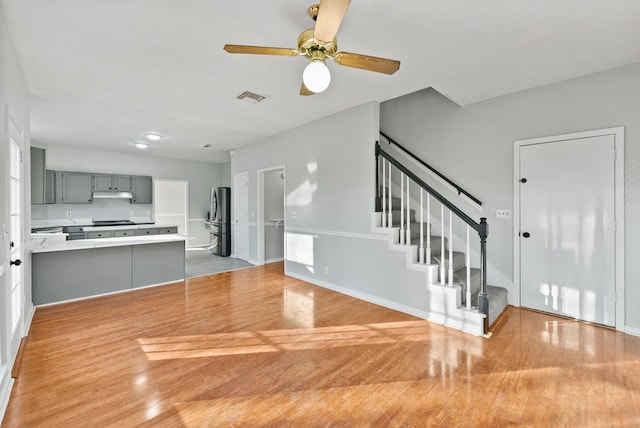 kitchen featuring light hardwood / wood-style flooring, ceiling fan, stainless steel fridge, gray cabinets, and kitchen peninsula