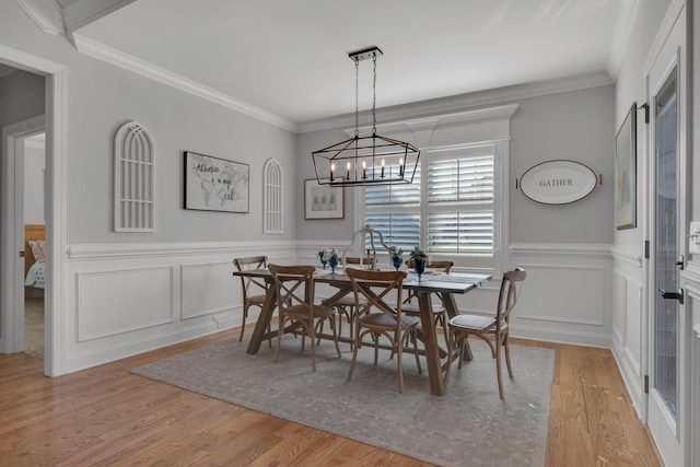 dining area featuring ornamental molding, light hardwood / wood-style floors, and a notable chandelier