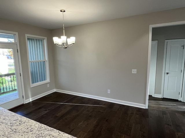 unfurnished dining area featuring dark hardwood / wood-style flooring and a notable chandelier