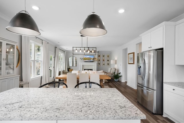 kitchen featuring white cabinets, stainless steel fridge, light stone countertops, and crown molding