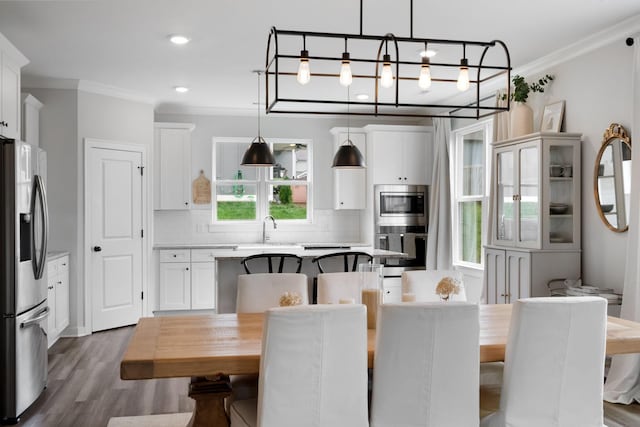 kitchen featuring hanging light fixtures, tasteful backsplash, white cabinets, a kitchen island, and appliances with stainless steel finishes