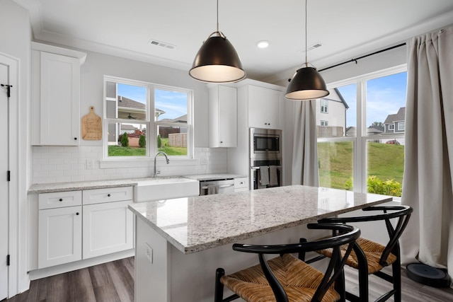 kitchen featuring decorative backsplash, white cabinets, and hanging light fixtures