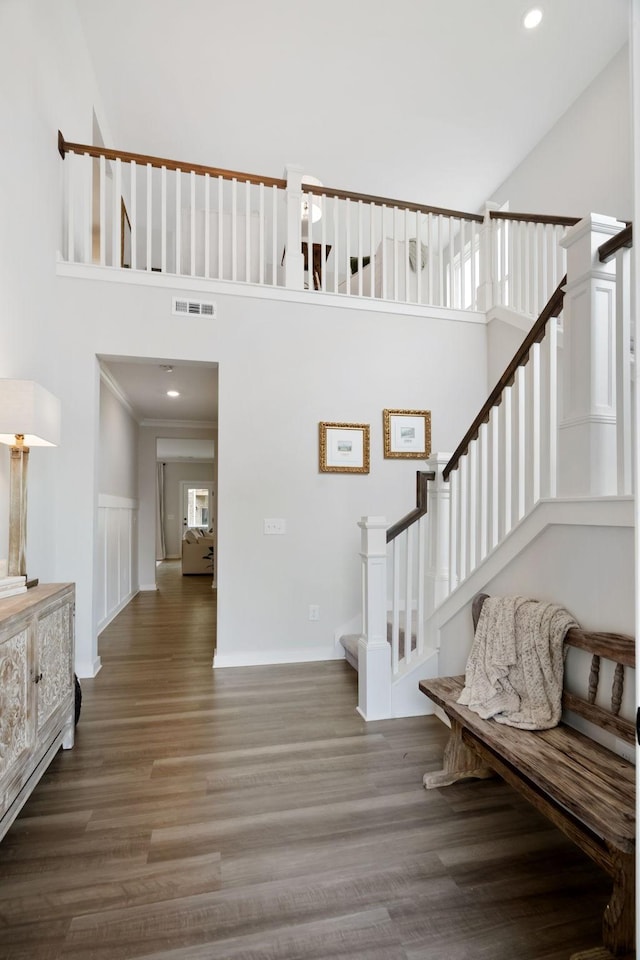 staircase with crown molding, a towering ceiling, and hardwood / wood-style flooring