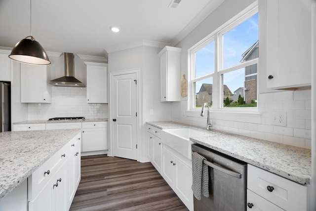 kitchen with white cabinetry, stainless steel appliances, wall chimney range hood, light stone counters, and pendant lighting