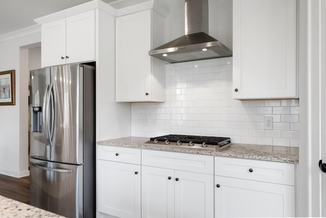 kitchen featuring decorative backsplash, stainless steel appliances, crown molding, wall chimney range hood, and white cabinets