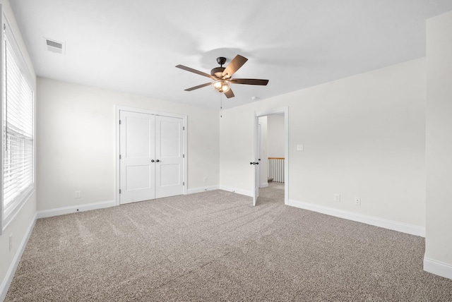 unfurnished bedroom featuring multiple windows, ceiling fan, a closet, and carpet