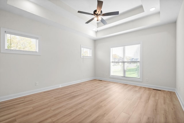 spare room featuring a tray ceiling, ceiling fan, and light hardwood / wood-style floors