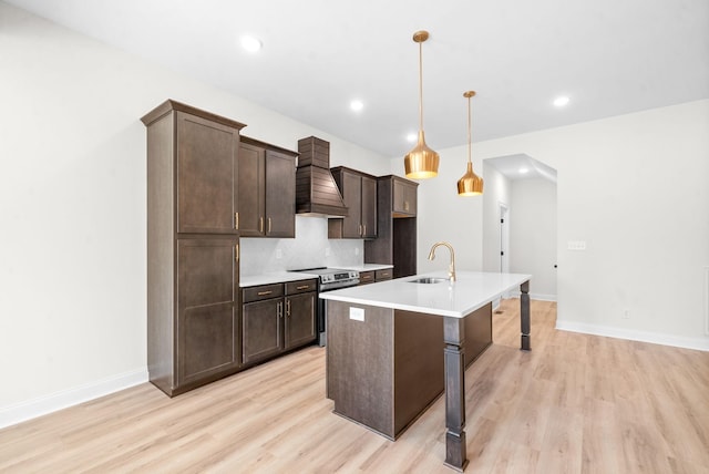 kitchen with decorative backsplash, a kitchen island with sink, stainless steel electric stove, sink, and pendant lighting