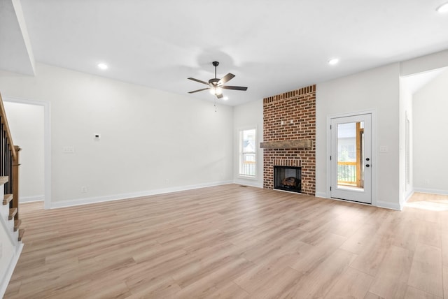 unfurnished living room featuring ceiling fan, plenty of natural light, light hardwood / wood-style flooring, and a brick fireplace