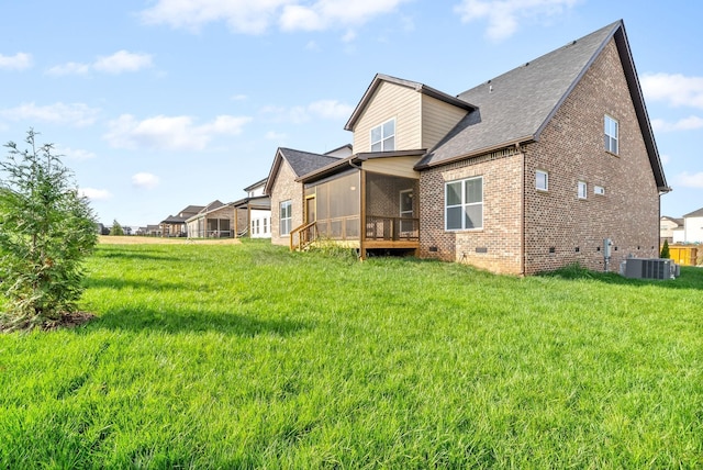 rear view of property with a sunroom, central AC unit, and a yard