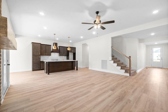 kitchen featuring ceiling fan, a center island, a kitchen breakfast bar, premium range hood, and pendant lighting