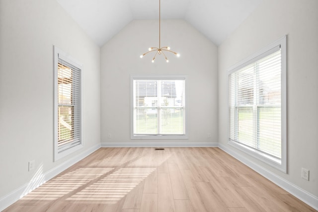 empty room featuring light wood-type flooring, lofted ceiling, and an inviting chandelier