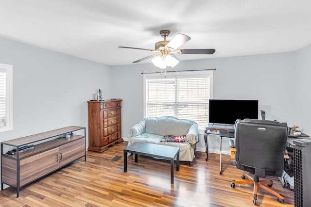 home office with light hardwood / wood-style floors and ceiling fan