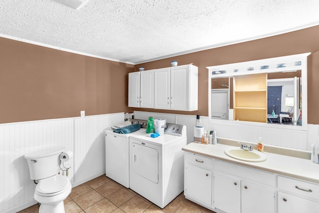 bathroom featuring tile patterned floors, ornamental molding, a textured ceiling, washing machine and clothes dryer, and toilet