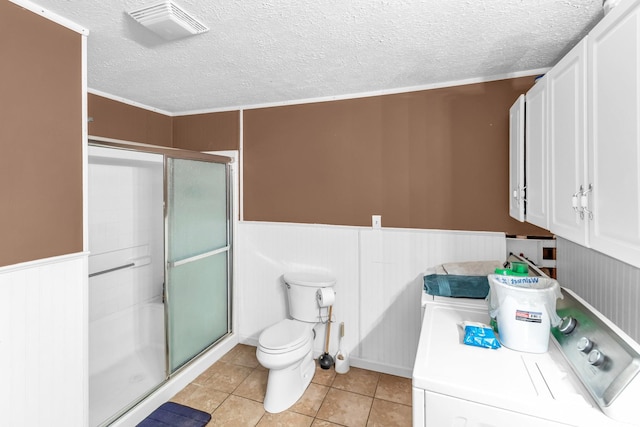 bathroom featuring tile patterned floors, toilet, ornamental molding, walk in shower, and washer / dryer