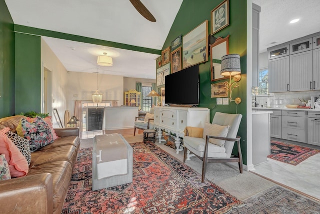 living room with ceiling fan, vaulted ceiling, a textured ceiling, and a wealth of natural light