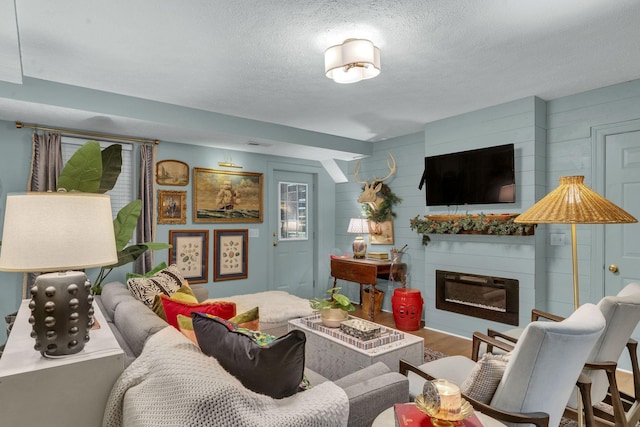 living room featuring a large fireplace, hardwood / wood-style floors, and a textured ceiling