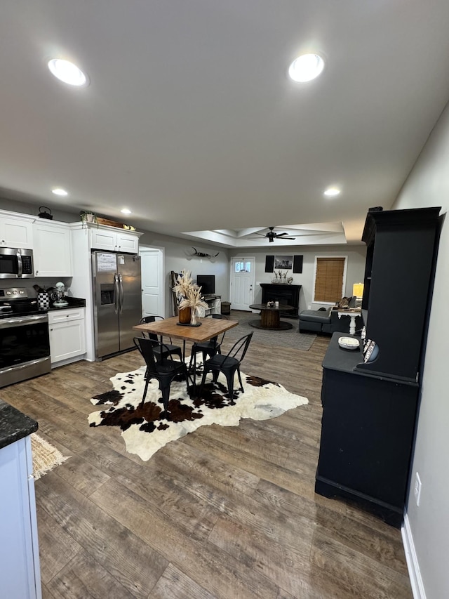 dining area with dark hardwood / wood-style floors, ceiling fan, and a tray ceiling