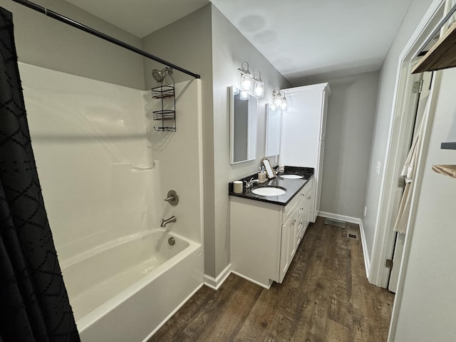 bathroom with hardwood / wood-style flooring, vanity, and shower / tub combination