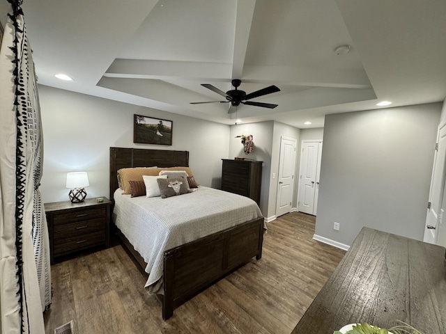 bedroom with ceiling fan, beamed ceiling, and dark wood-type flooring