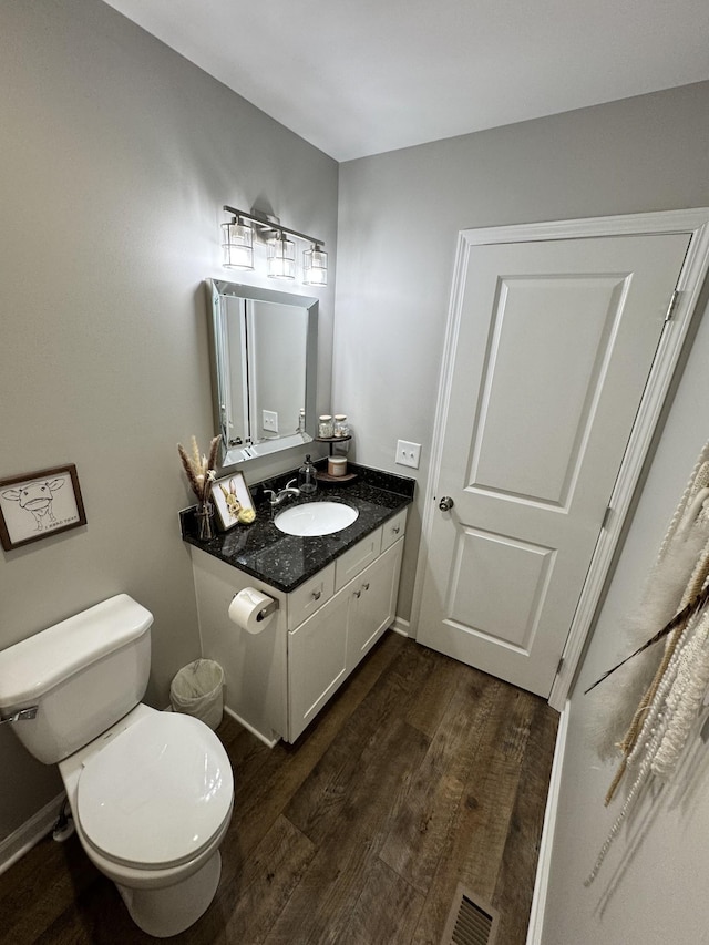 bathroom with wood-type flooring, vanity, and toilet